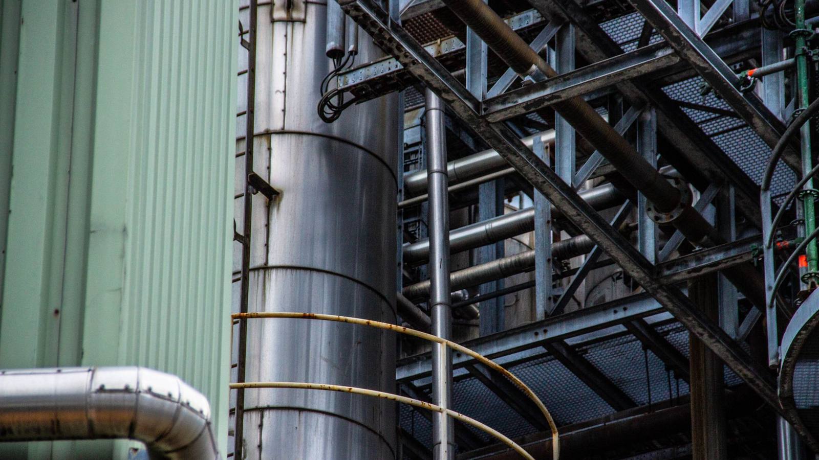 Steel frames, a cylindrical tank and pipework at an industrial plant