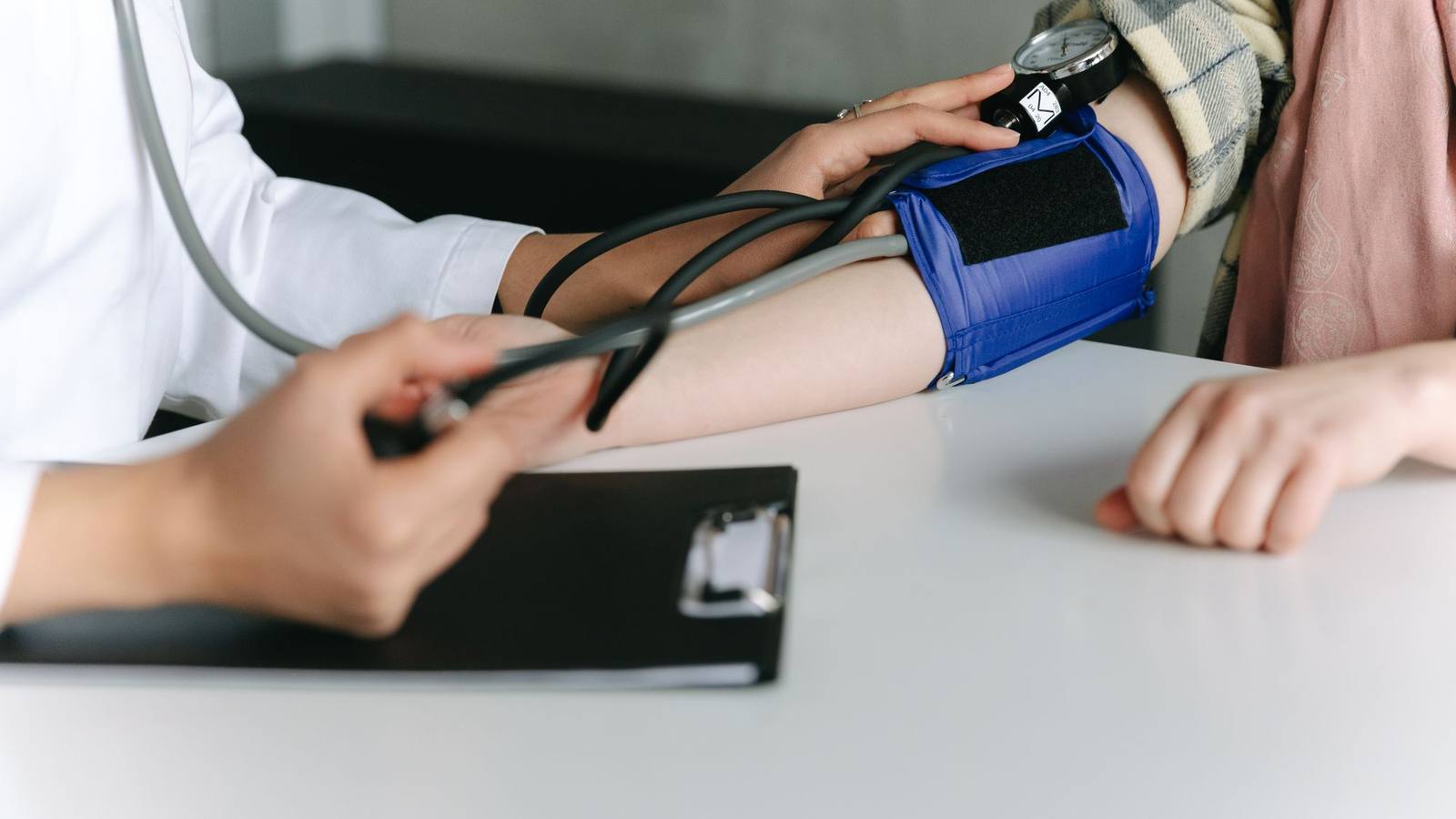 A healthcare worker measuring a patient's blood pressure with a sphygmomanometer.