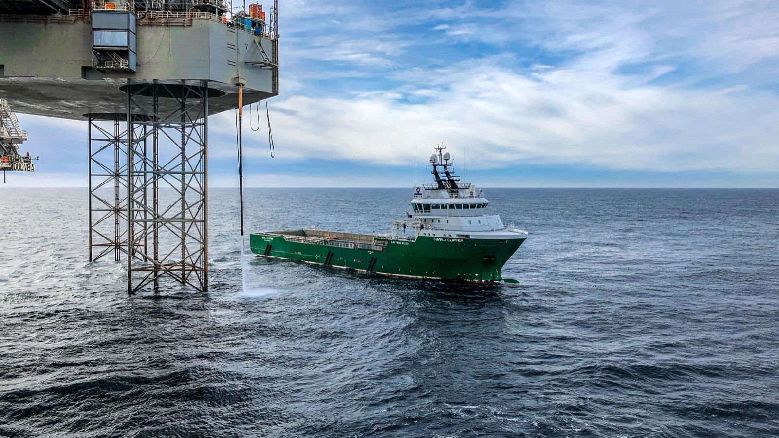 An offshore platform at sea with a supply vessel alongside